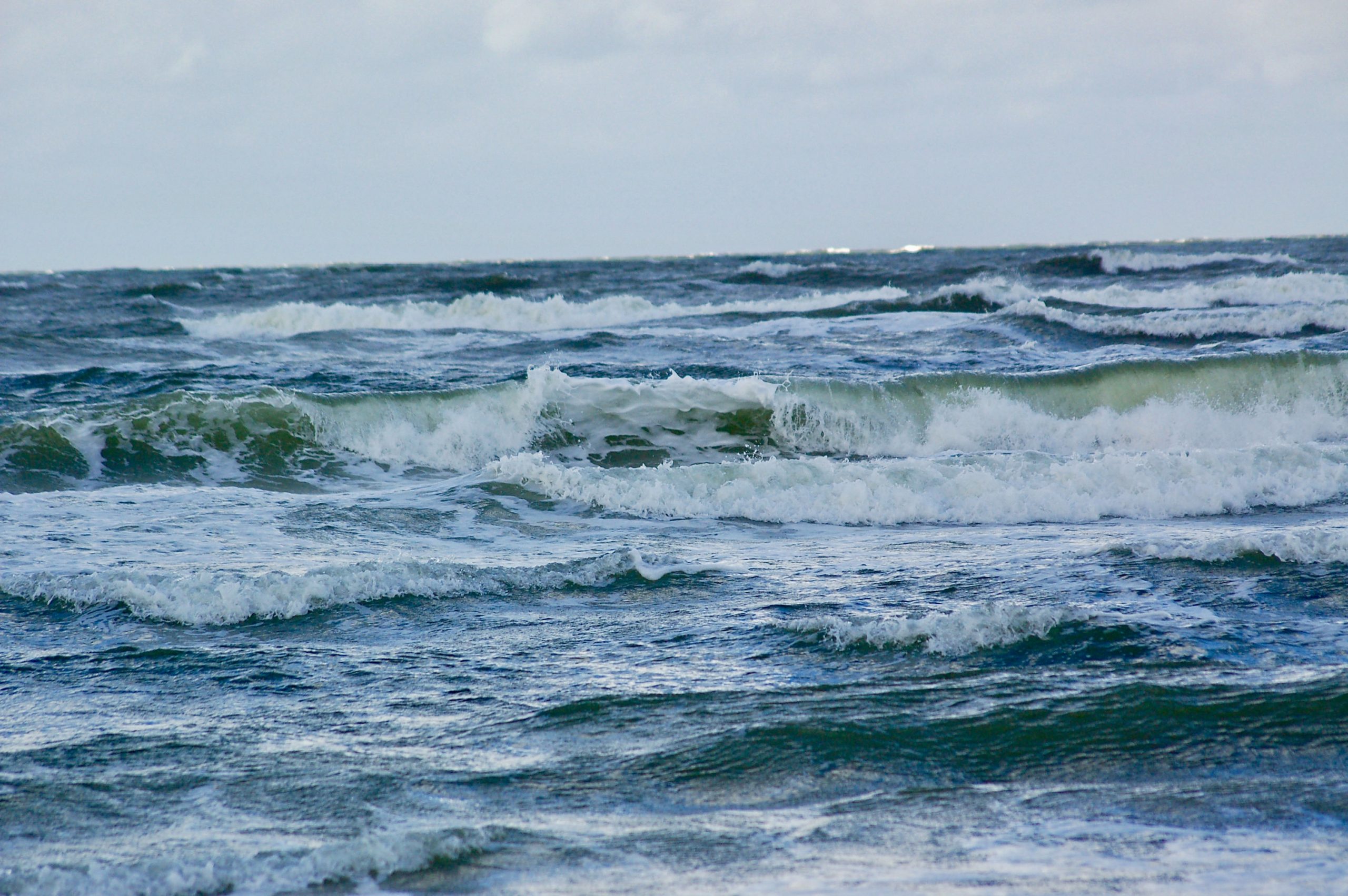 Blick auf das Meer. Wellen mit Schaumkronen rollen ans Ufer.